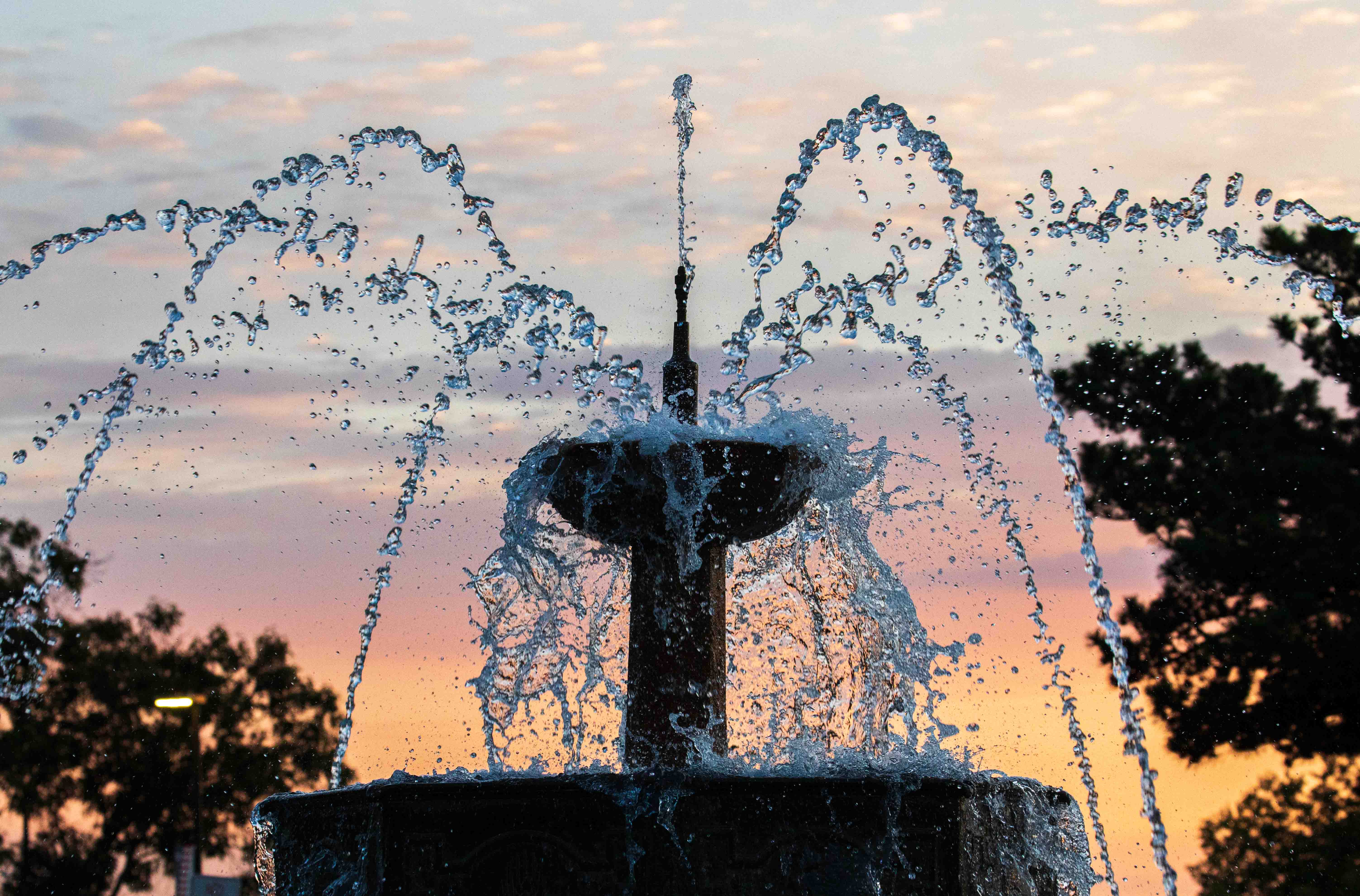 The fountain at the west entrance to Jayhawk Boulevard at sunset. The photo captures individual droplets as they fall.